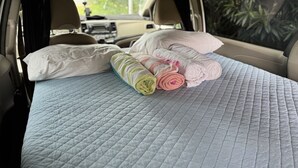 L'intérieur d'une voiture aménagé avec un lit, des oreillers et une couverture matelassée.