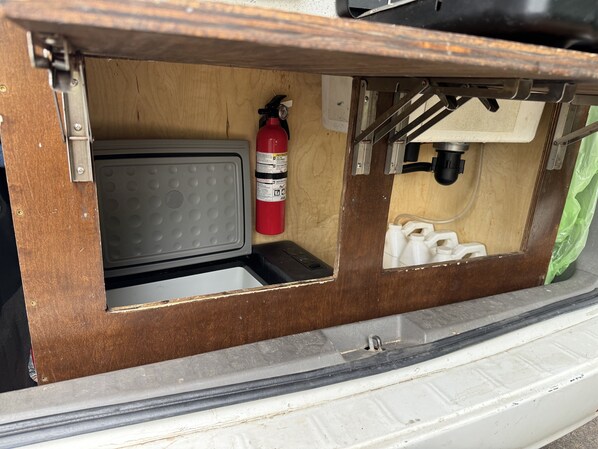 A compact kitchenette with a microwave, a red fire extinguisher, and a water dispenser.