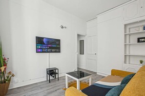 Relax in this stylish living room with a flat-screen TV, comfortable sofa, and modern shelving unit.