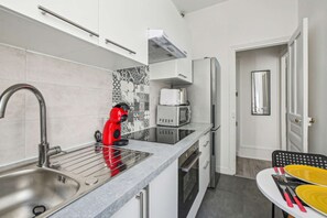 Enjoy cooking in this well-lit kitchen with a stainless steel sink, coffee machine, and microwave.