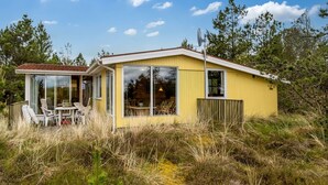 Une cabine jaune dotée d’une paroi vitrée, d’un coin repas et d’une petite terrasse.