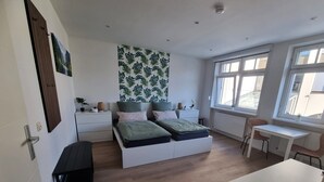 Un dormitorio moderno con cama, mesitas de noche, escritorio y ventana.