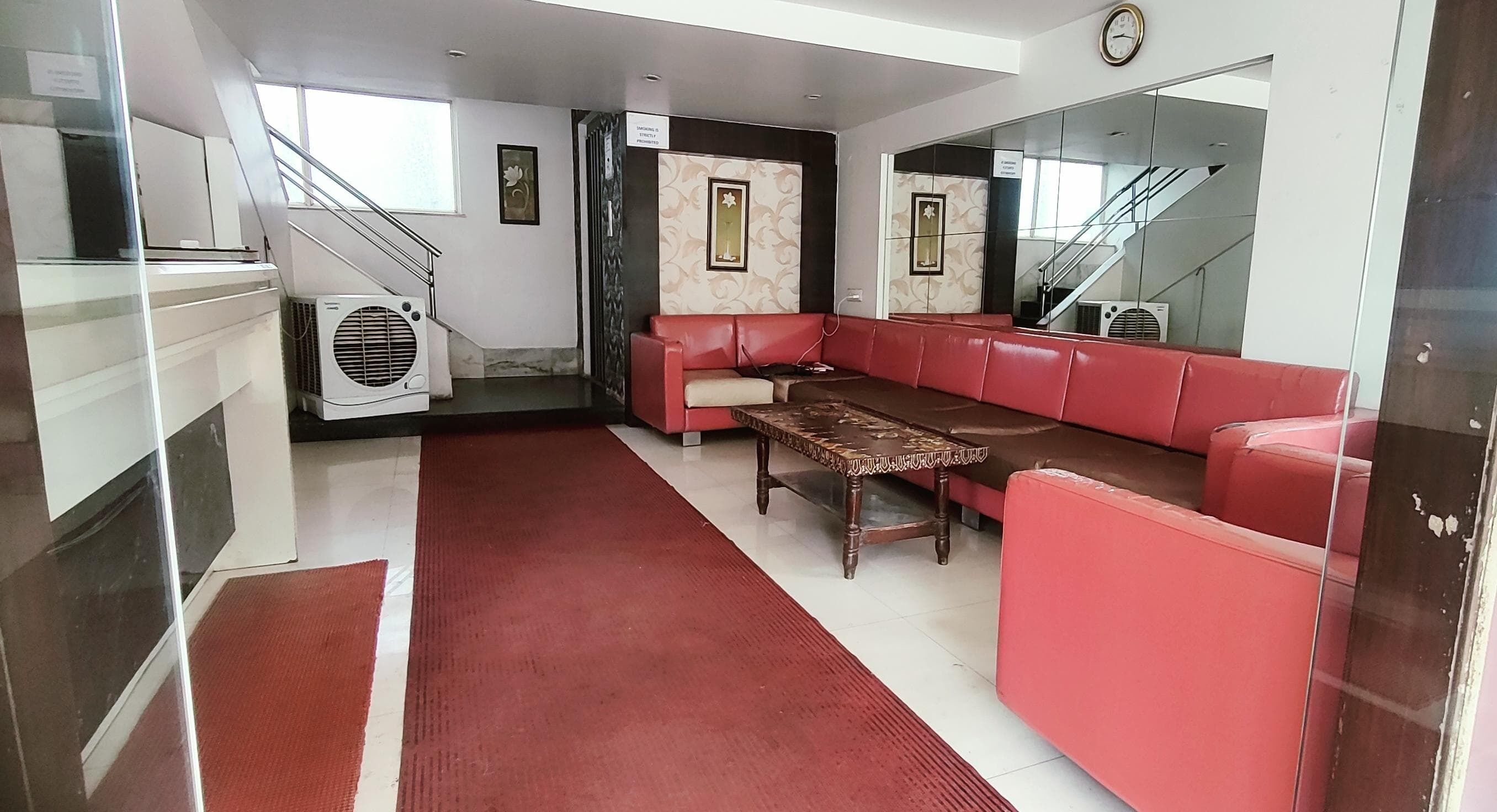 Un vestíbulo moderno con un sofá rojo, una mesa de centro de madera y una escalera.