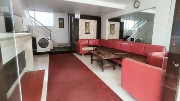 Un vestíbulo moderno con un sofá rojo, una mesa de centro de madera y una escalera.