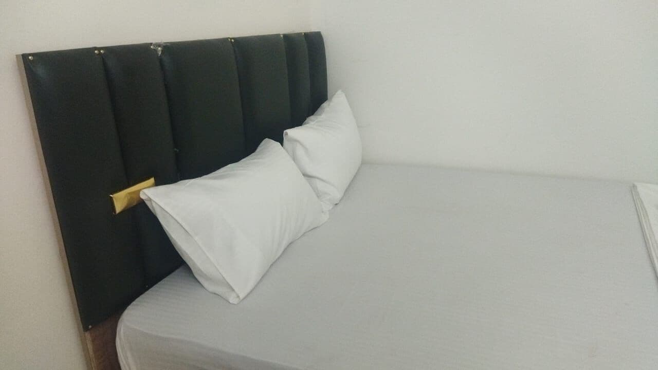 Una cama con cabecera oscura y almohada blanca.