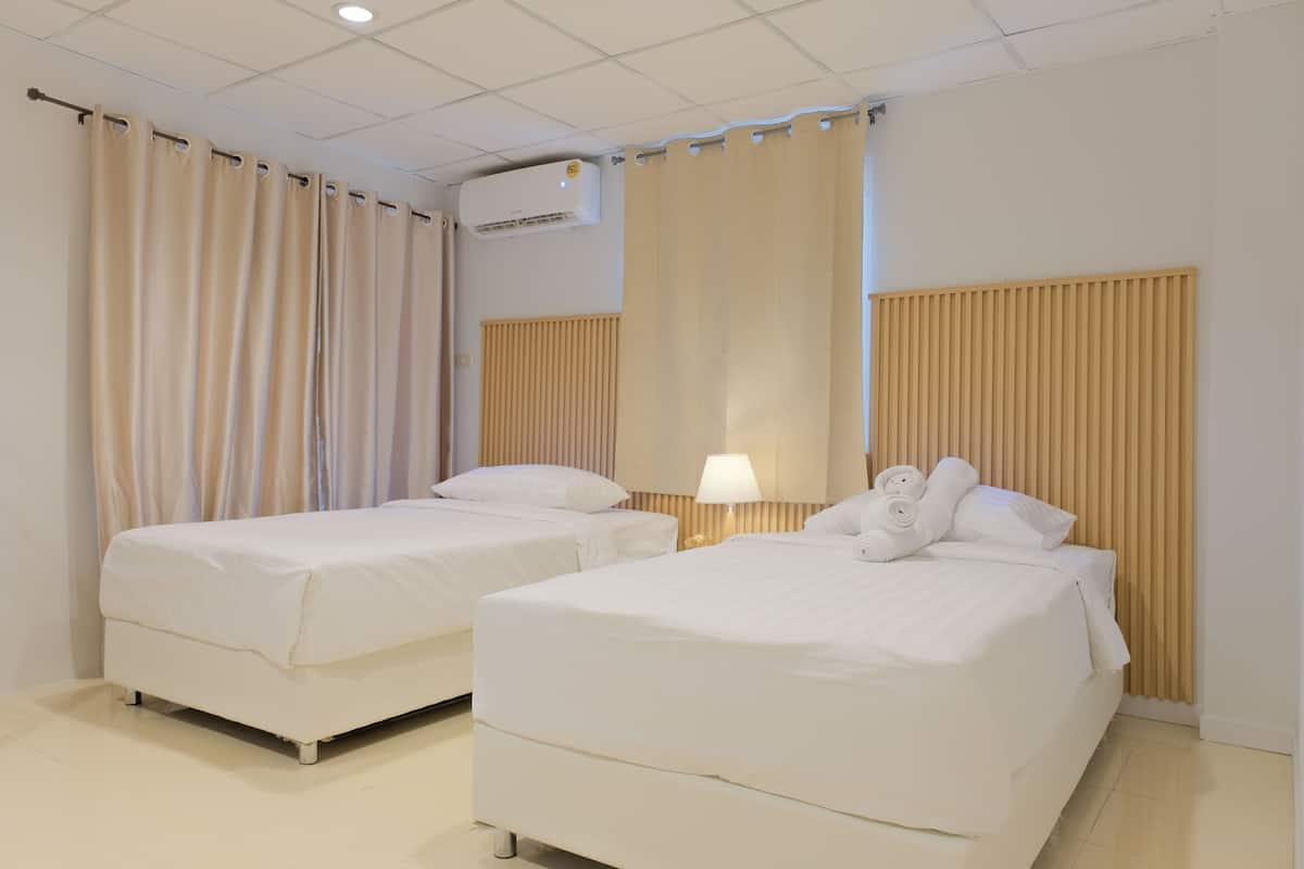 A hotel room with two single beds, a ceiling air conditioner, and a wooden panel wall.