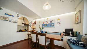 Un comedor con una mesa y sillas de madera, una lámpara colgante y una pared decorada con motivos náuticos.