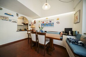 Un comedor con una mesa y sillas de madera, una lámpara colgante y una pared decorada con motivos náuticos.