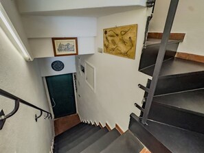 A staircase with a handrail, a door at the bottom, and a wall-mounted map.
