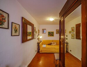 A hallway with a yellow sofa, a mirror, and framed pictures on the walls.