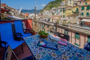 Une terrasse avec une table, des chaises, un saladier rempli de fruits et une brochure d’une agence de voyages.