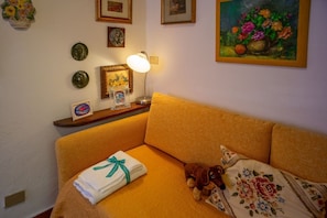 A room with a bed, a lamp, a teddy bear, and a painting on the wall.