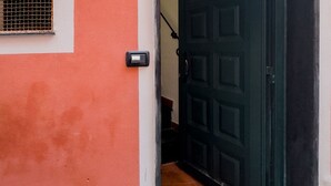 A door with a security device, a window with a metal grill, and a red wall.