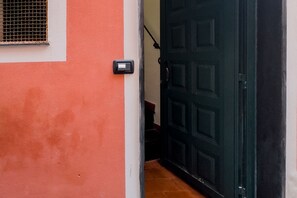 A door with a security device, a window with a metal grill, and a red wall.