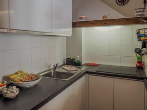 A kitchen with white cabinets, a black countertop, and various kitchen items including a bowl of food, a dish rack, and a sink. - La Maison de la Mer with Terrace and AC (Vernazza)