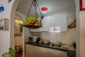 Une cuisine équipée d’un panier à fruits suspendu, d’un four à micro-ondes, d’un évier et de placards.