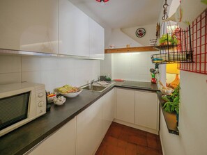 A compact kitchen with white cabinets, a microwave, a sink, and a small countertop area. - La Maison de la Mer with Terrace and AC (Vernazza)
