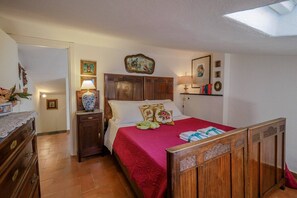 A bedroom with a wooden headboard, a red bedspread, and a nightstand with a lamp. - La Maison de la Mer with Terrace and AC (Vernazza)