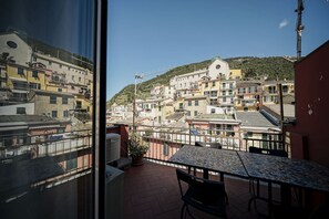 A balcony with a table and chairs, overlooking a hillside of colorful buildings.