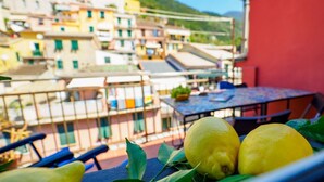 A balcony with a table and chairs, a railing, and a view of colorful buildings in the background.