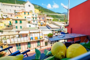 A balcony with a table and chairs, a railing, and a view of colorful buildings in the background.