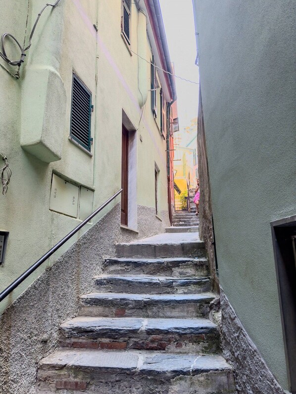 A narrow street with a stone staircase leading to a building entrance.