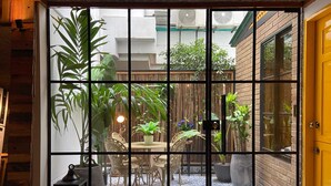 Un patio con piso de baldosas, plantas en macetas y mobiliario exterior.