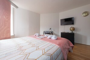 Quarto de hotel com uma cama, televisão de tela plana, um globo e um relógio na parede.