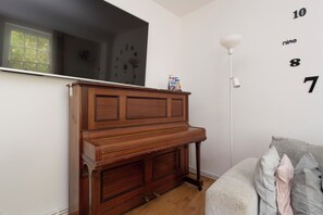 A room with a wooden piano, a white wall with numbers, a lamp, and a window. - Quiet location in Central London, near Paddington, Regent Park, Lord's Cricket (London)