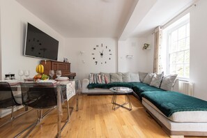 En moderne stue med spiseplads, sofaarrangement og stort vindue.