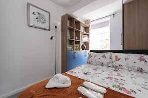 A bedroom with a bed, a wardrobe, a shelf with books, and a window. - Quiet location in Central London, near Paddington, Regent Park, Lord's Cricket (London)