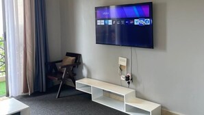 Un saló modern amb un televisor de pantalla plana fixat a la paret, un moble blanc sota i un sòl amb moqueta gris.