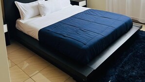 Un dormitori amb un llit, una tauleta de nit i una finestra amb cortines.
