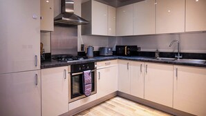 A modern kitchen with stainless steel appliances, light-colored cabinets, and a wooden floor. - Convenient 2 Bedroom Apartment in Crawley (Crawley)
