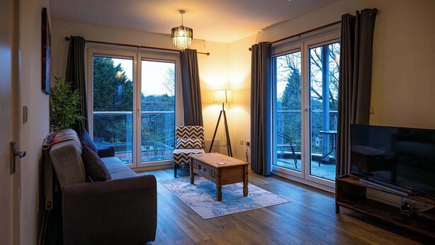 A living room with a sofa, a coffee table, a lamp, and a TV. - Convenient 2 Bedroom Apartment in Crawley (Crawley)