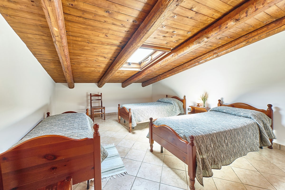 Een slaapkamer met drie houten bedden, een dakraam en een betegelde vloer.