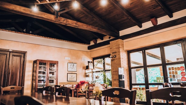 Interior de restaurante con vigas de madera, una columna de ladrillo y un ventanal con vistas.