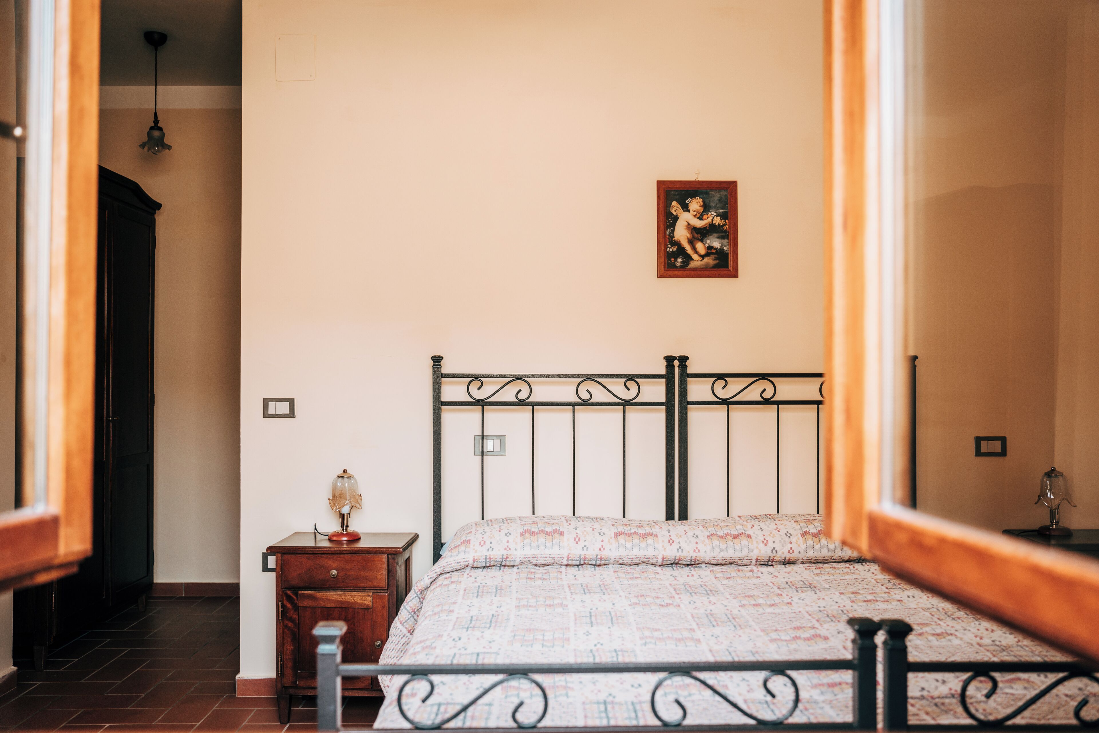 A bedroom with a bed, a nightstand, a lamp, and a wall-mounted picture.
