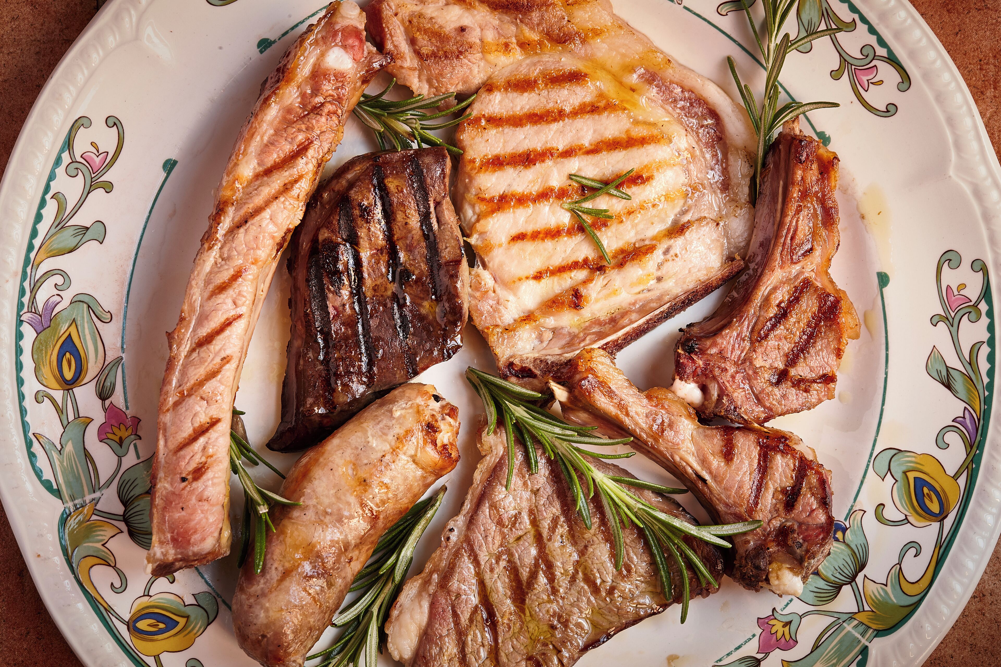 Un plato de chuletas de cordero a la parrilla y costillas adornadas con romero.