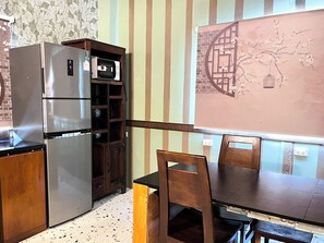 Une cuisine équipée d’un réfrigérateur, d’un four à micro-ondes, de meubles de rangement en bois, d’une table à manger avec des chaises et d’un mur décoratif.