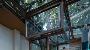 Una cocina moderna con refrigerador empotrado, recinto de vidrio y piso de madera.