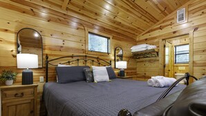A wooden cabin bedroom with a bed, bedside tables, lamps, and a mirror. - Cozy cabin-Great Location (Hochatown)