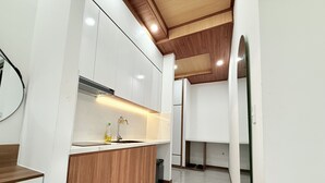 A modern kitchen with white cabinets, wooden accents, and a tiled floor. - Hasa Da Lat Hotel and Apartment (Xuan Huong - Da Lat)