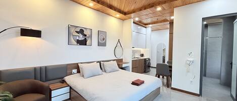 A modern bedroom with a wooden ceiling, a large bed, bedside tables, a desk, and a wardrobe.