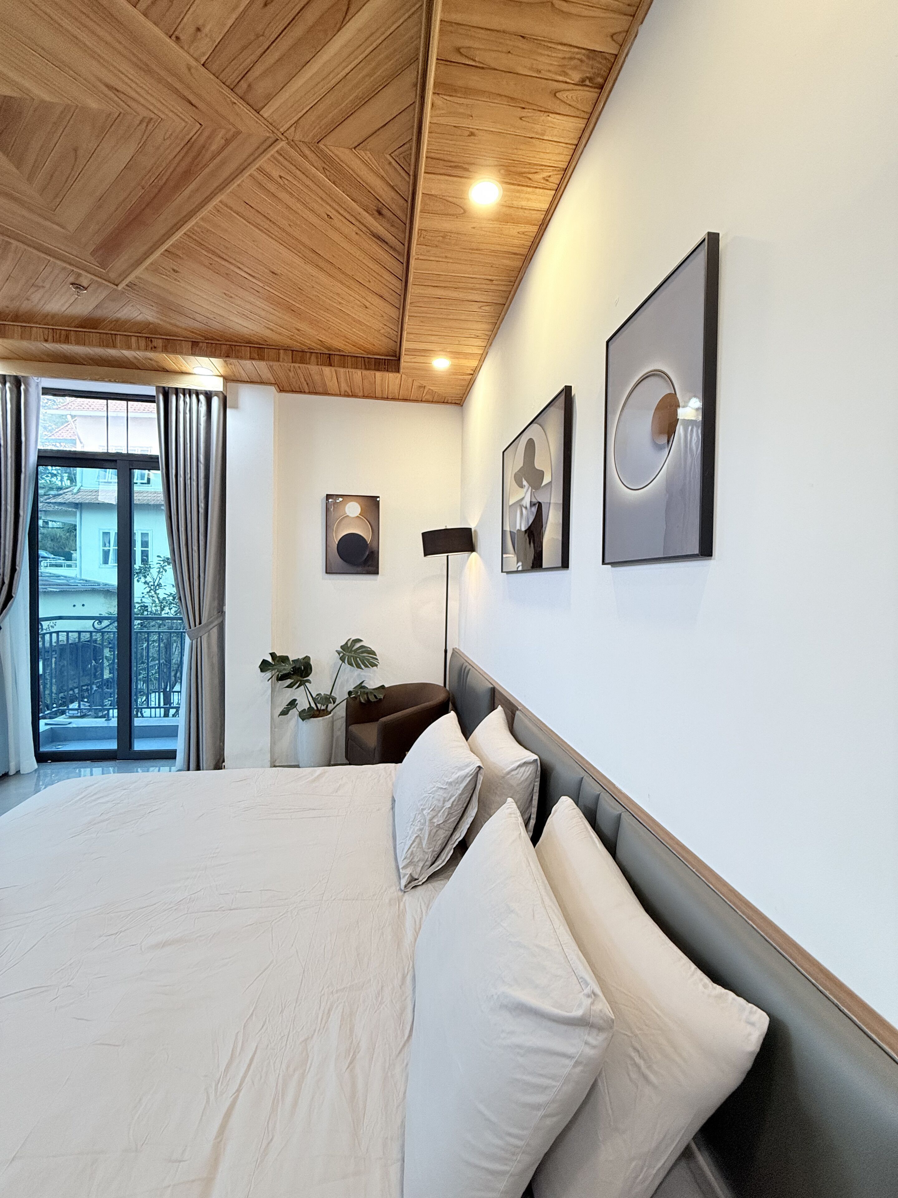 A bedroom with a large bed, a wooden ceiling, and a balcony view.