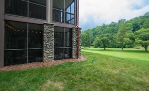 A modern building with large windows and stone pillars, surrounded by a well-maintained lawn and trees.