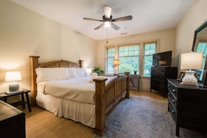A bedroom with a wooden bed, a ceiling fan, a TV, and a dresser. - Scenic 2BR Condo w/ Porch + Pool Near Slope/Trails | Free Tickets (Maggie Valley)