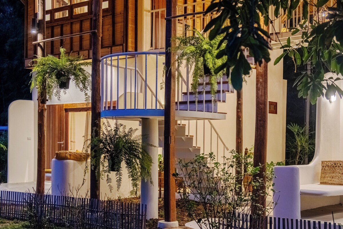 A modern building with a white exterior, wooden balconies, and lush greenery.