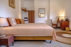 A bedroom with a bed, bedside table, lamp, dresser, mirror, and a small rug. - Bamboo Nest at SangGaDee (San Kamphaeng)