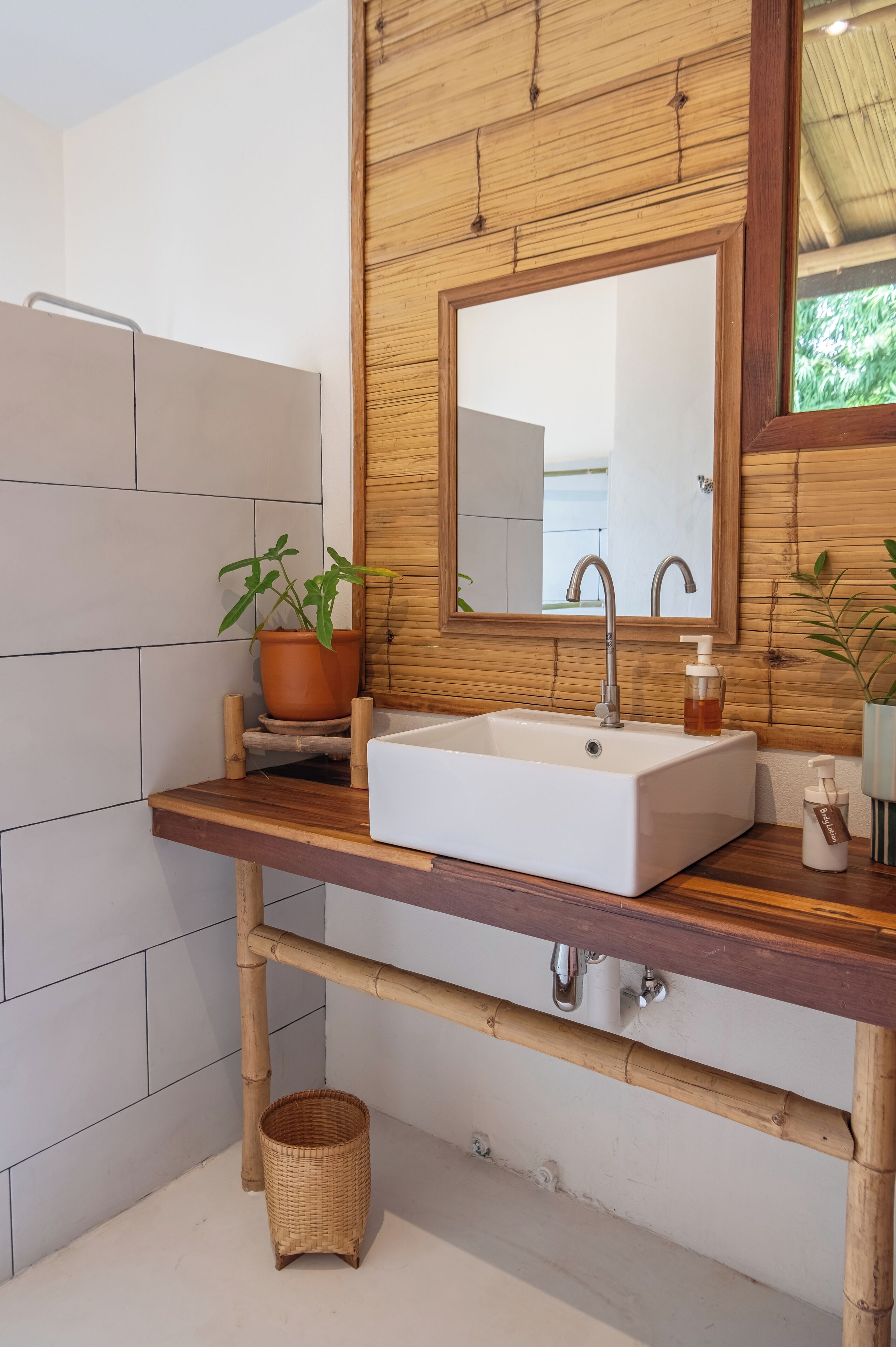 A bathroom with a wooden vanity, white sink, and a mirror above it.